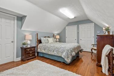 bedroom with vaulted ceiling, wood finished floors, and baseboards