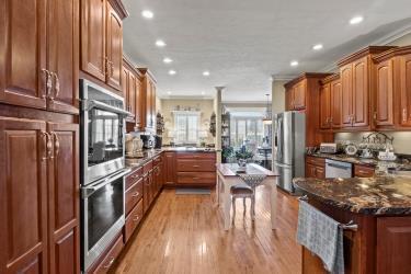 kitchen featuring crown molding, stainless steel appliances, light wood-type flooring, dark stone counters, and a peninsula