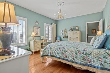 bedroom with multiple windows, wood finished floors, and a notable chandelier