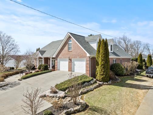 view of front of house with a garage, a front yard, concrete driveway, and brick siding