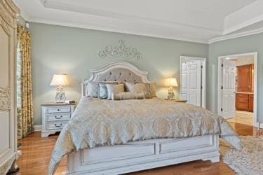 bedroom featuring ornamental molding, a raised ceiling, and wood finished floors