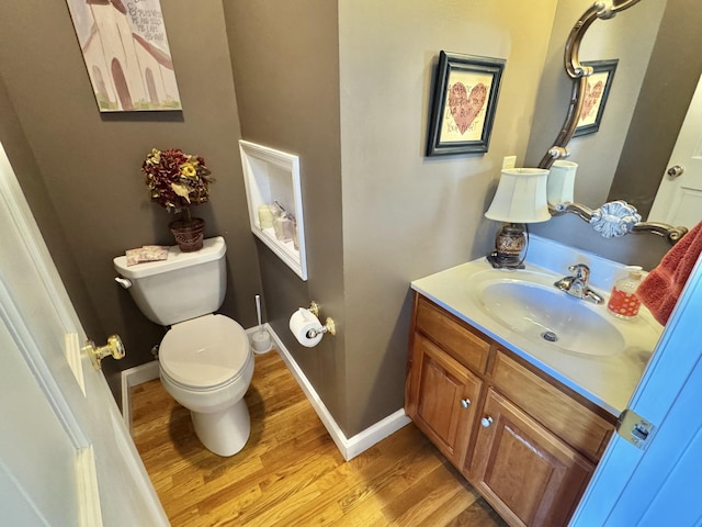 bathroom with toilet, hardwood / wood-style floors, and vanity