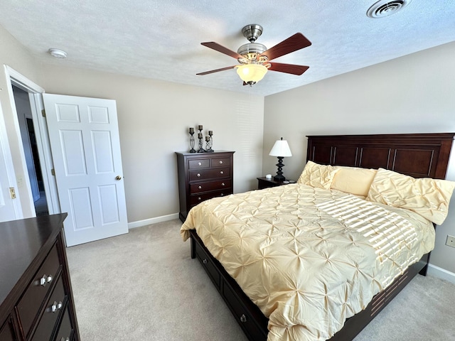 bedroom with ceiling fan, light colored carpet, and a textured ceiling