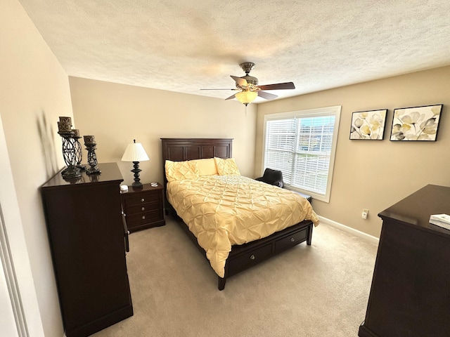 bedroom featuring light carpet, ceiling fan, and a textured ceiling