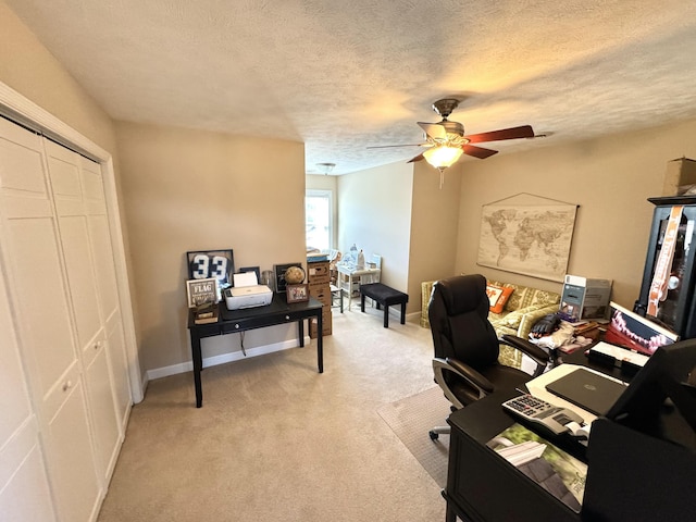 carpeted home office featuring a textured ceiling and ceiling fan