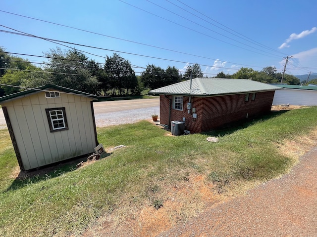 view of property exterior with a lawn, cooling unit, and a shed