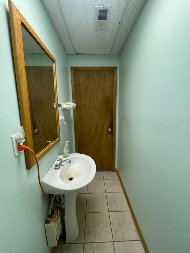 bathroom featuring a paneled ceiling and tile patterned flooring