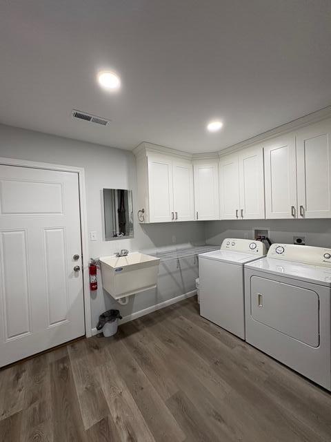 washroom featuring dark wood-style flooring, cabinet space, visible vents, a sink, and independent washer and dryer