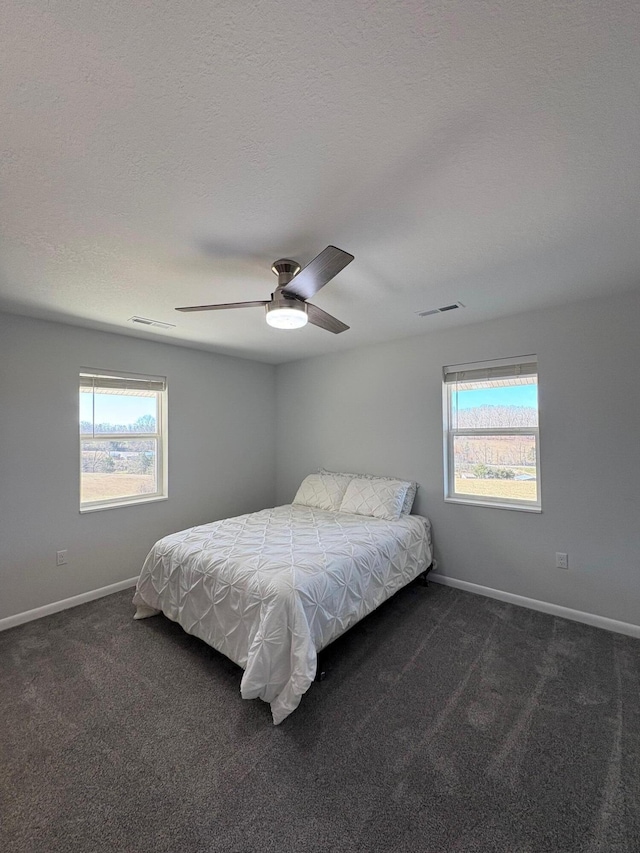 bedroom featuring dark colored carpet, multiple windows, visible vents, and baseboards