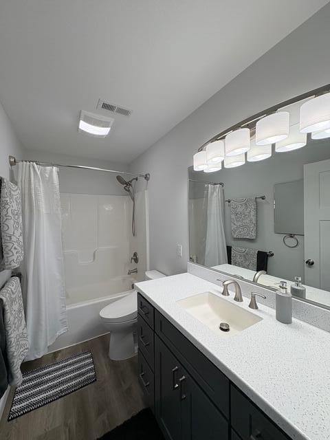 full bath with shower / bath combo, visible vents, toilet, wood finished floors, and vanity