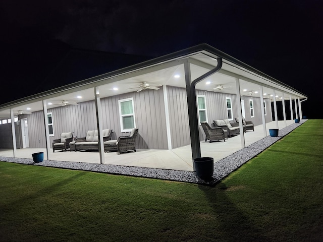 back of house at twilight with an outdoor hangout area, a yard, a patio area, and a ceiling fan