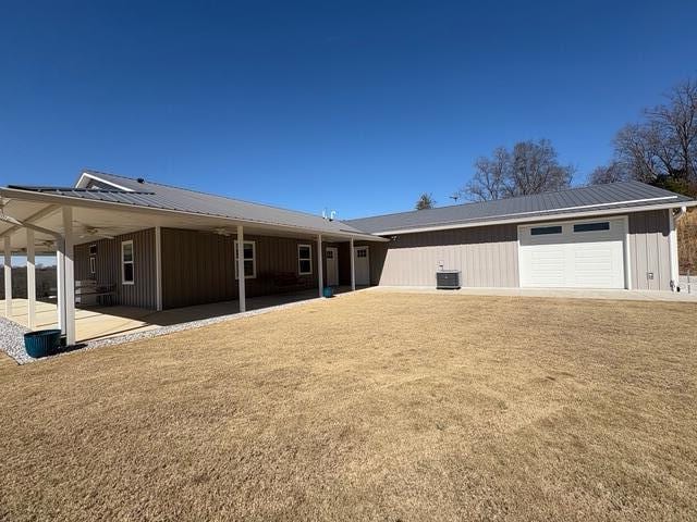 back of property featuring metal roof, central AC, and a lawn