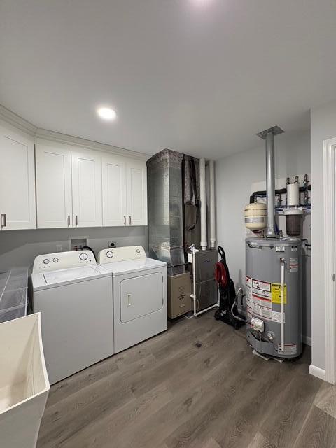 washroom with gas water heater, wood finished floors, cabinet space, heating unit, and washing machine and clothes dryer