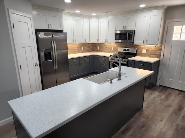 kitchen featuring white cabinets, decorative backsplash, dark wood-style floors, stainless steel appliances, and a sink