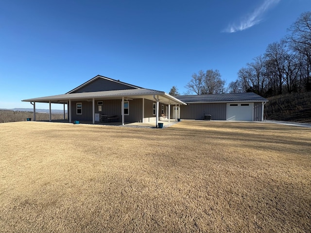 view of front of property featuring a porch, an attached carport, a garage, and a front lawn