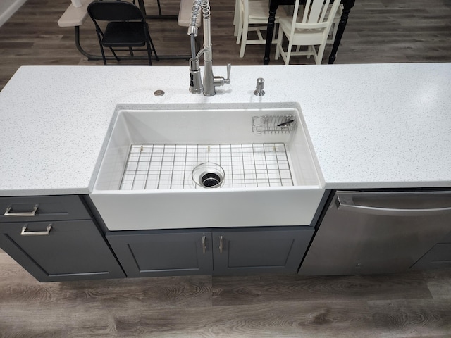 details featuring a sink, dark wood-type flooring, light countertops, and dishwasher