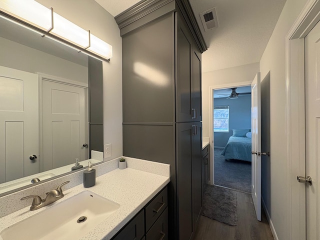 ensuite bathroom with baseboards, visible vents, wood finished floors, ensuite bathroom, and vanity