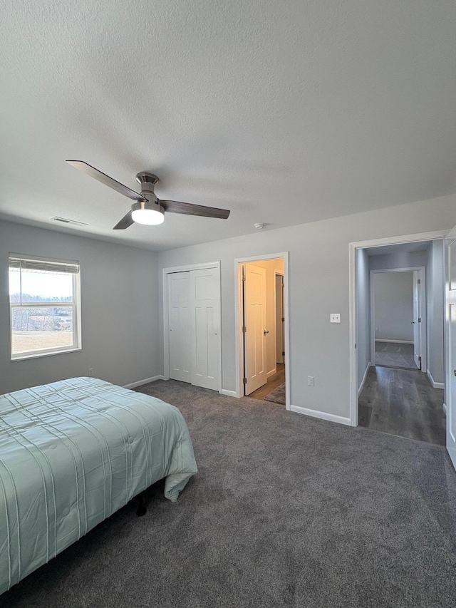 bedroom with dark colored carpet, visible vents, a ceiling fan, a textured ceiling, and baseboards