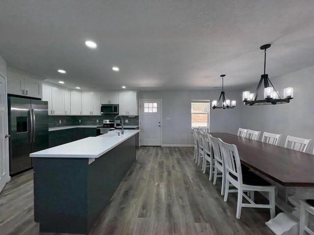 kitchen featuring white cabinets, a kitchen island with sink, appliances with stainless steel finishes, and light countertops