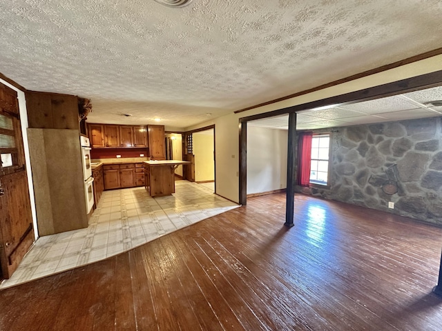 4140 Chavis Rd, Cosby, TN 37722 - kitchen with light wood finished floors, open floor plan, brown cabinetry, a kitchen island, and a textured ceiling