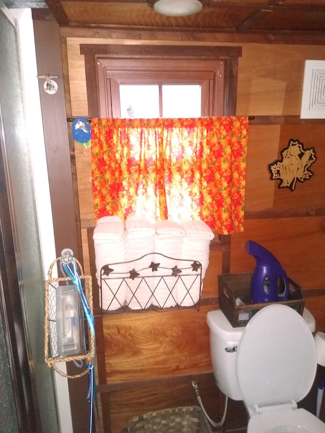 bathroom with toilet and wooden walls