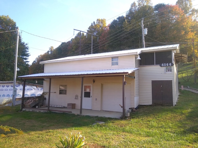 back of property featuring a garage and a yard