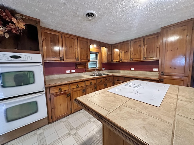 4140 Chavis Rd, Cosby, TN 37722 - kitchen with white appliances, brown cabinets, a textured ceiling, tile counters, and light flooring