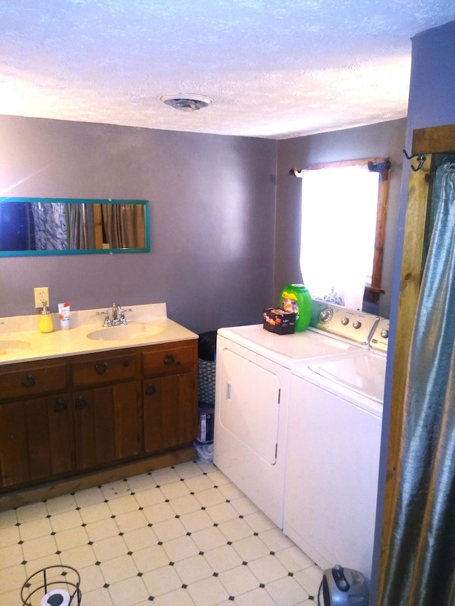 laundry area featuring washing machine and clothes dryer, sink, and a textured ceiling