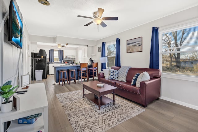 living room with crown molding, wood-type flooring, and ceiling fan