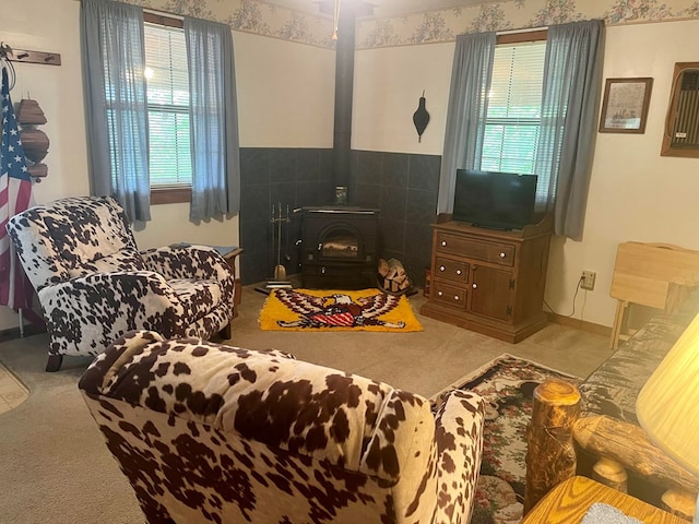 living room with carpet floors, a wood stove, and a wealth of natural light