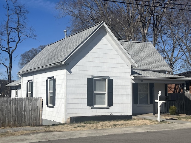 view of front of home with a shingled roof and fence