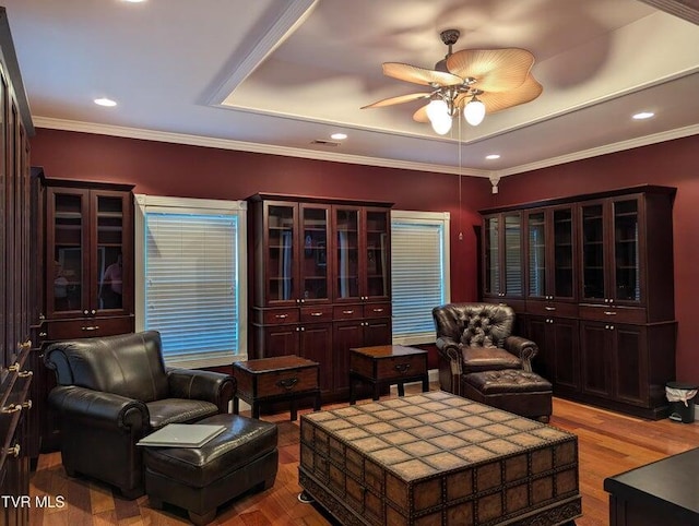 living room with ornamental molding, a tray ceiling, ceiling fan, and light hardwood / wood-style floors