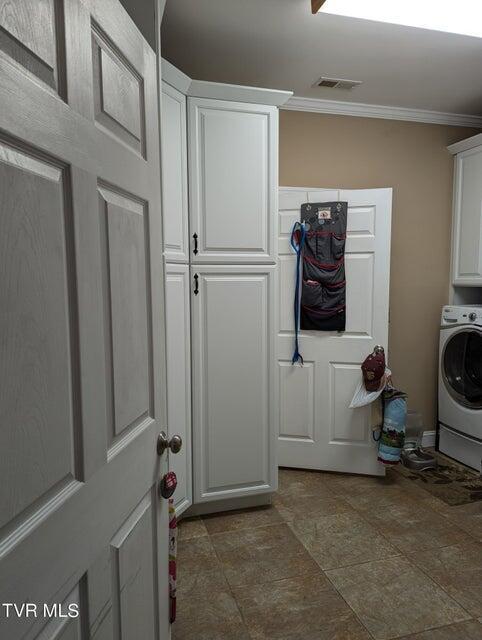 washroom with washer / clothes dryer, crown molding, and cabinets