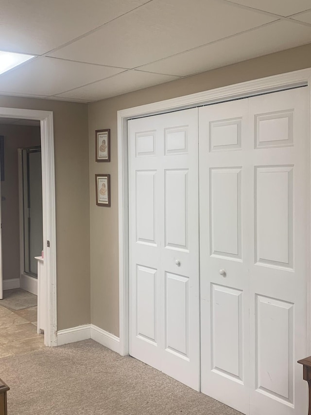 interior space featuring a drop ceiling, light colored carpet, and a closet