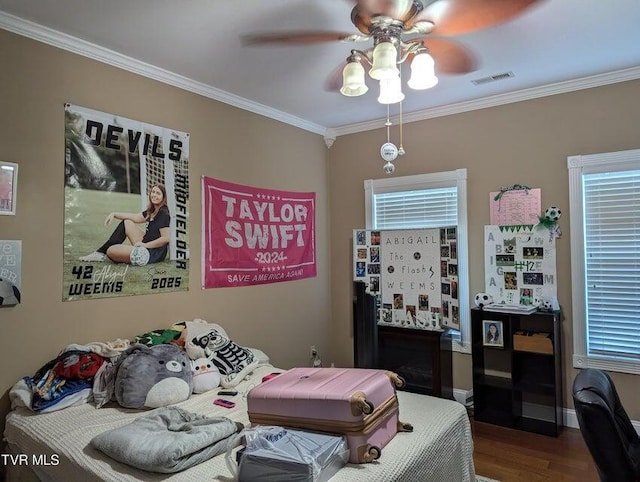 bedroom featuring ceiling fan, wood-type flooring, crown molding, and multiple windows