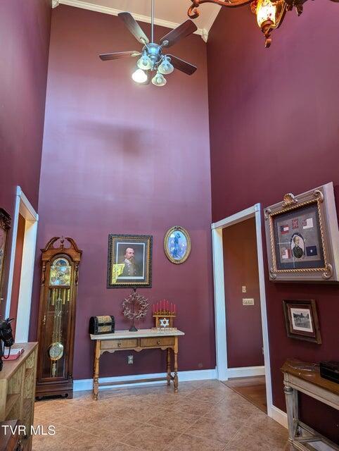 foyer with tile patterned floors, ceiling fan, and a high ceiling