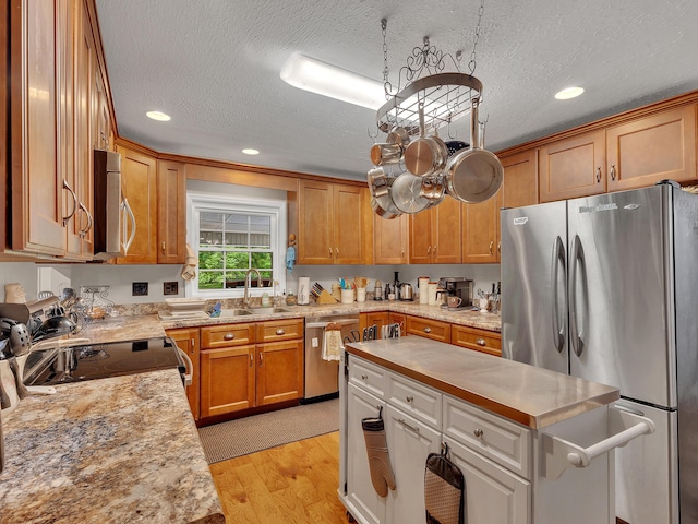 6525 Idumea Rd, Corryton, TN 37721 - kitchen featuring appliances with stainless steel finishes, a textured ceiling, light wood-style flooring, a sink, and a kitchen island