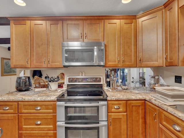 6525 Idumea Rd, Corryton, TN 37721 - kitchen featuring appliances with stainless steel finishes, brown cabinets, and light stone countertops