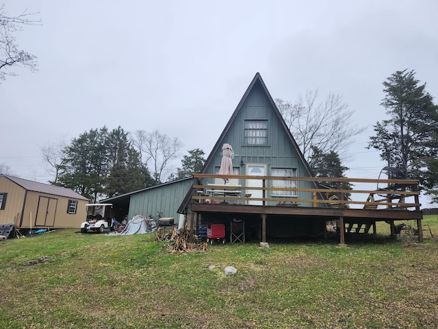 back of property with a deck, a shed, and a lawn