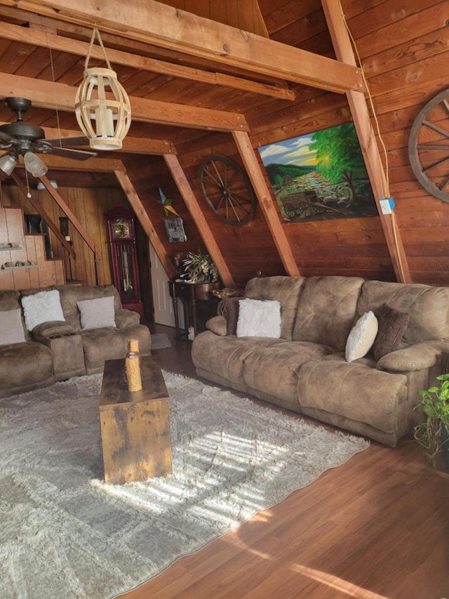 unfurnished living room featuring ceiling fan, wooden walls, hardwood / wood-style floors, and vaulted ceiling with beams