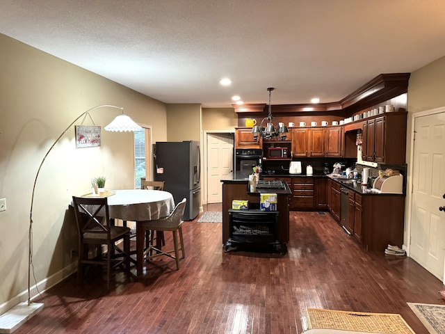 kitchen featuring a center island, dark wood-style flooring, dark countertops, an inviting chandelier, and appliances with stainless steel finishes