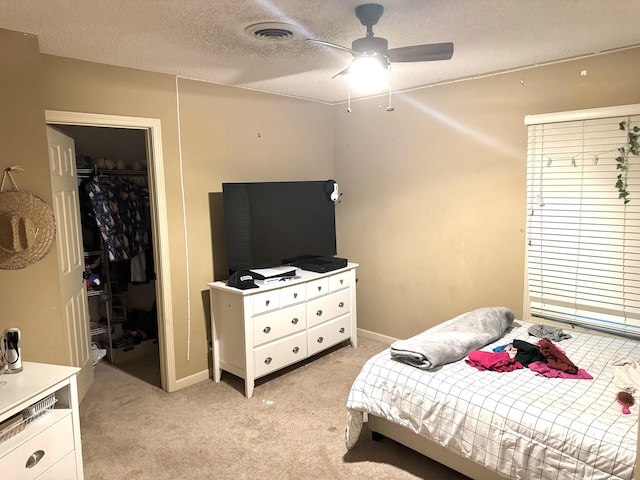 bedroom with a textured ceiling, light carpet, visible vents, baseboards, and a closet