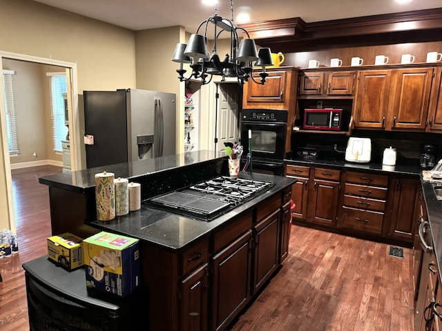 kitchen with black appliances, a kitchen island, a chandelier, and wood finished floors