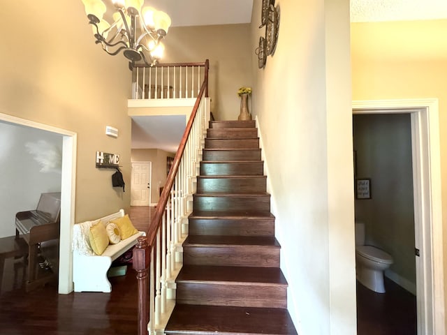 staircase with a chandelier, baseboards, and wood finished floors