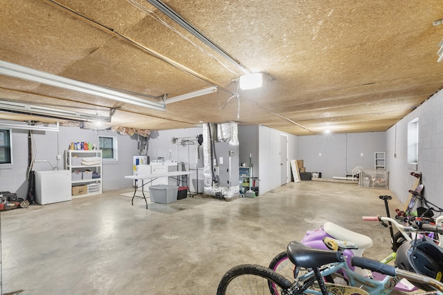 basement featuring washer and dryer, heating unit, and fridge