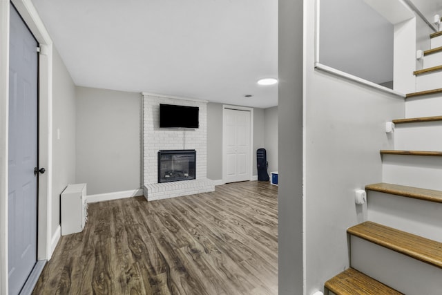 unfurnished living room featuring hardwood / wood-style floors and a brick fireplace