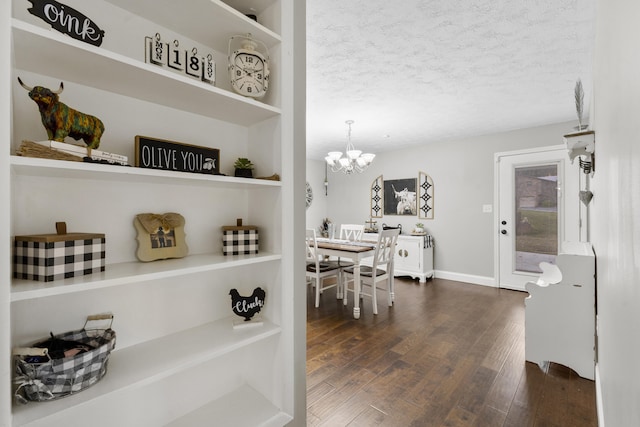 dining area featuring a chandelier, a textured ceiling, built in features, and dark wood-type flooring