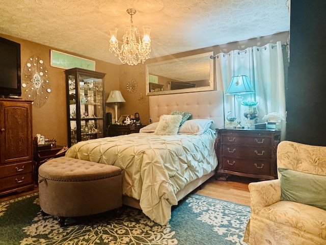bedroom featuring a textured ceiling, wood finished floors, and a notable chandelier