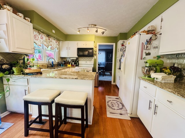 kitchen with white appliances, white cabinetry, dark wood-style floors, and a sink