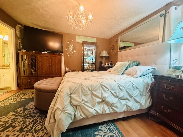 bedroom with an inviting chandelier, a textured ceiling, and wood finished floors